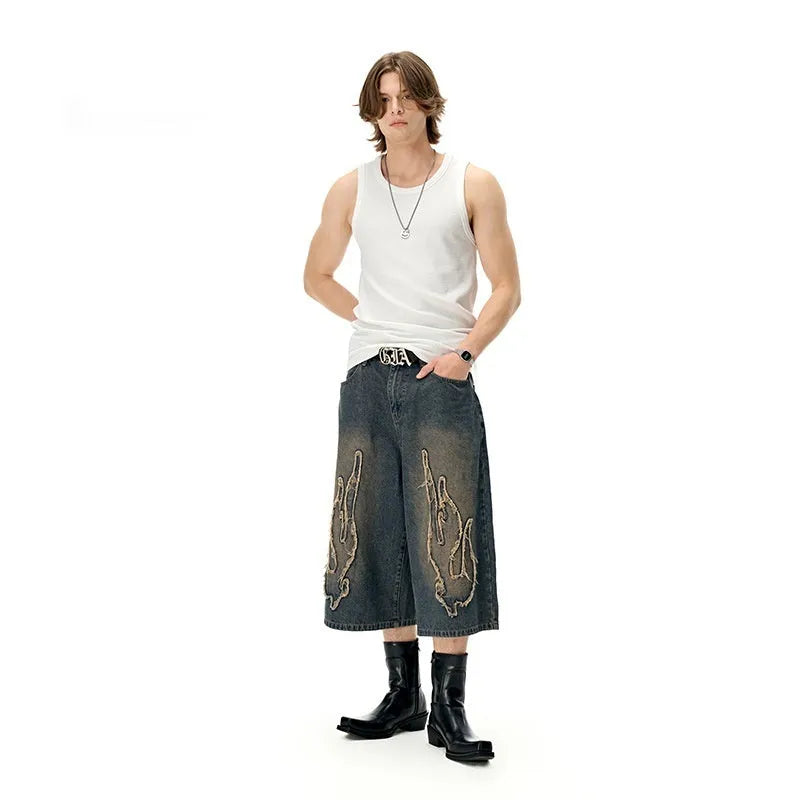 Men's black denim shorts with flame embroidery patches showing straight-leg cropped design