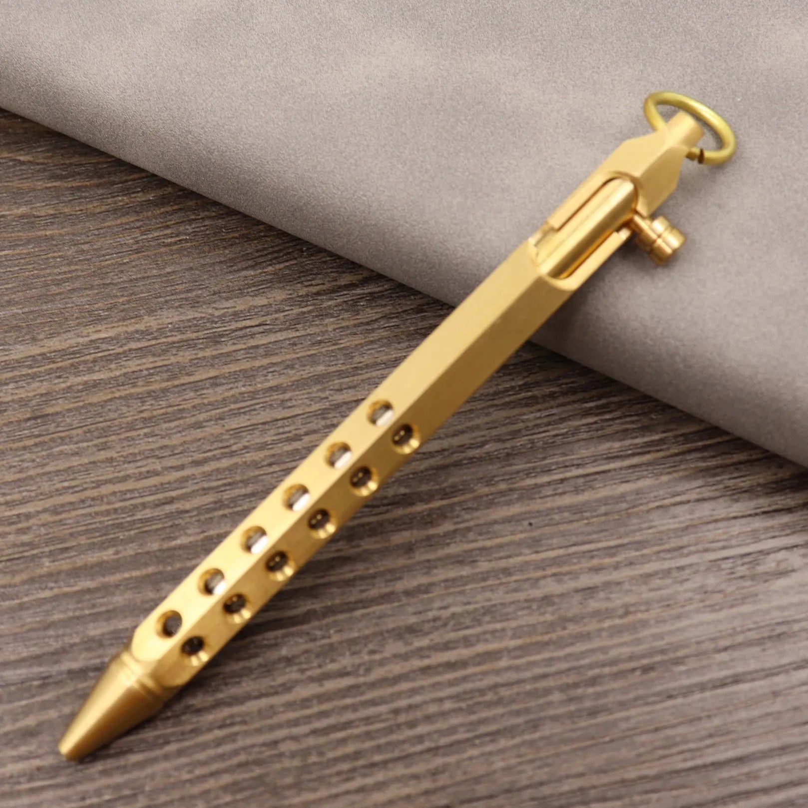 Retro brass tactical pen with cylindrical barrel and six-ring grip, shown with press mechanism extended