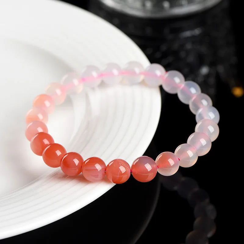 Natural gradient Yanyuan agate bracelet with spherical beads on a white background.