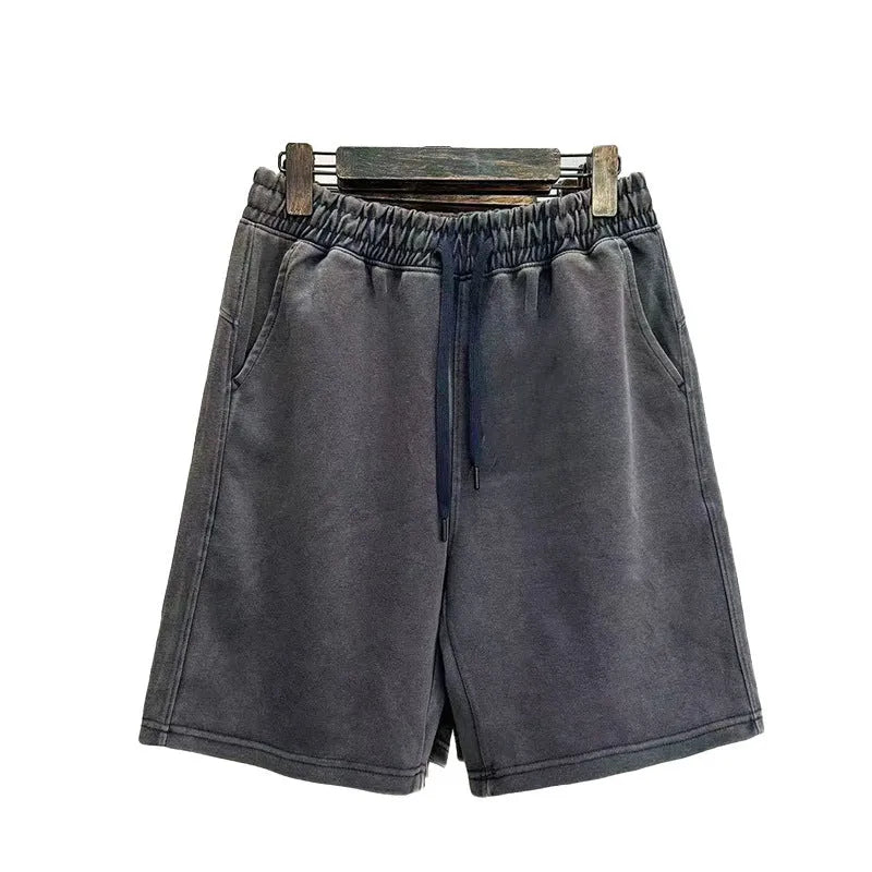Man wearing charcoal black distressed cotton casual shorts with a loose straight fit.