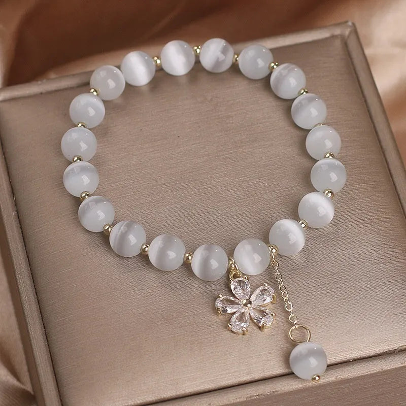 White cat's eye crystal bracelet for women with a small flower tassel and a morganite-coloured safety buckle.