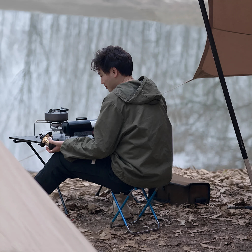 Black aluminium alloy folding stool in outdoor setting, shown in folded and unfolded positions.