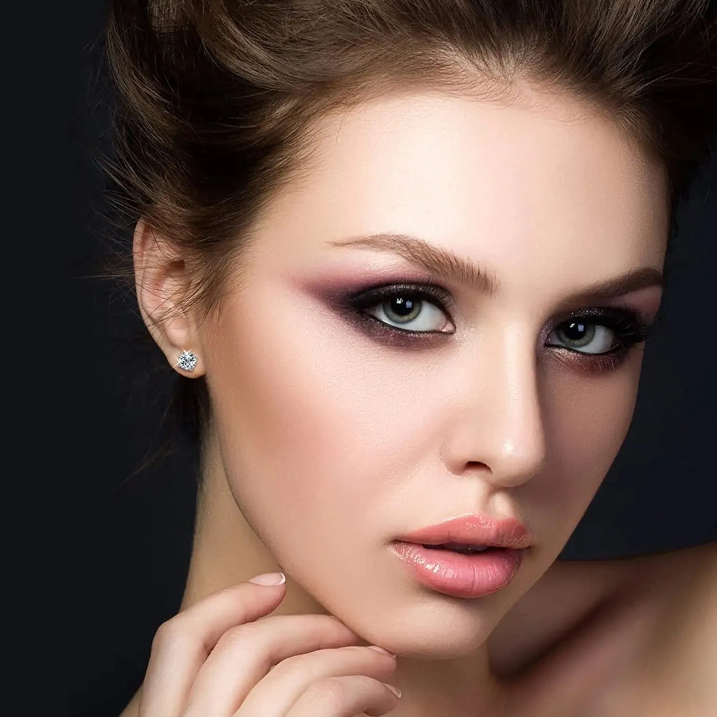 Silver four-claw set moissanite stud earrings with geometric shape and screw-back fittings.