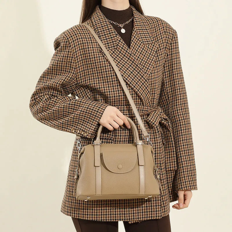 Black genuine leather ladies handbag with single shoulder strap, showing contrast lock and stitching.