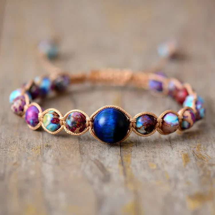 Hand woven friendship bracelet with adjustable cord and single Emperor Stone bead on a plain background.