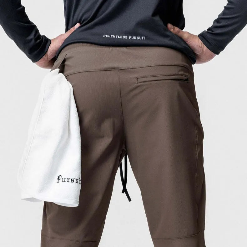 Men's grey loose-fit running pants with ankle ties on a gym floor