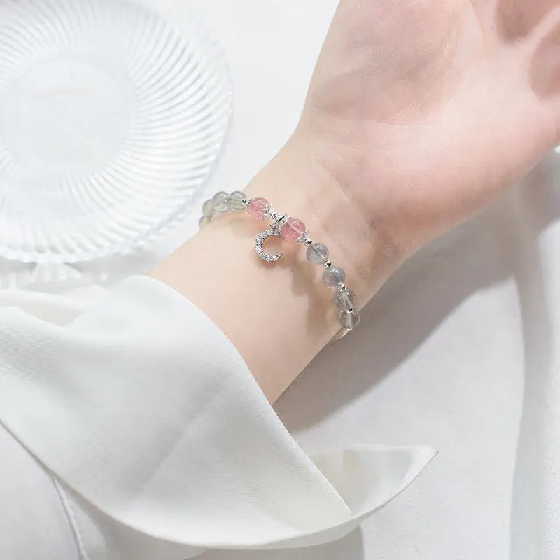 Handmade adjustable bracelet with a natural moonstone and silver crescent moon charm on a wrist.