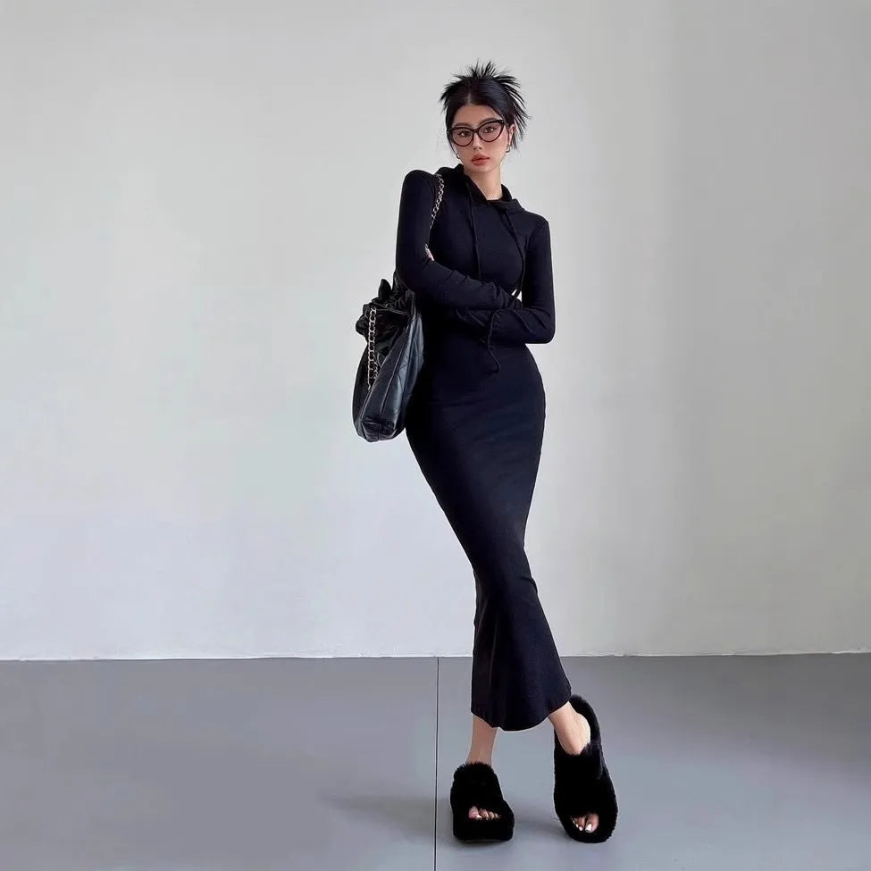 A woman wearing a light grey hooded sheath dress with long sleeves, showcasing the high waist and over-the-knee length.