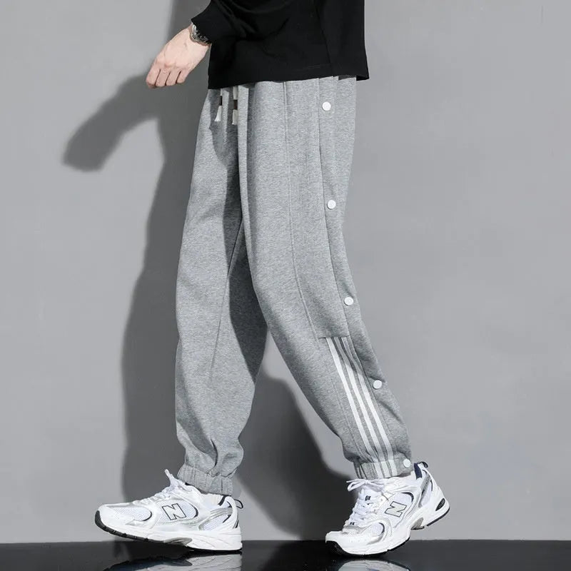 Men's black high-waist sweatpants with ankle-tied cuffs and a drawstring waist on a grey background.