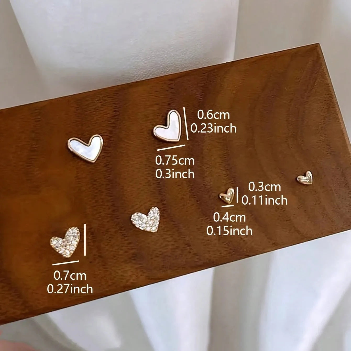 Three pairs of women's heart-shaped alloy earrings in gold, black, white, and pink colours