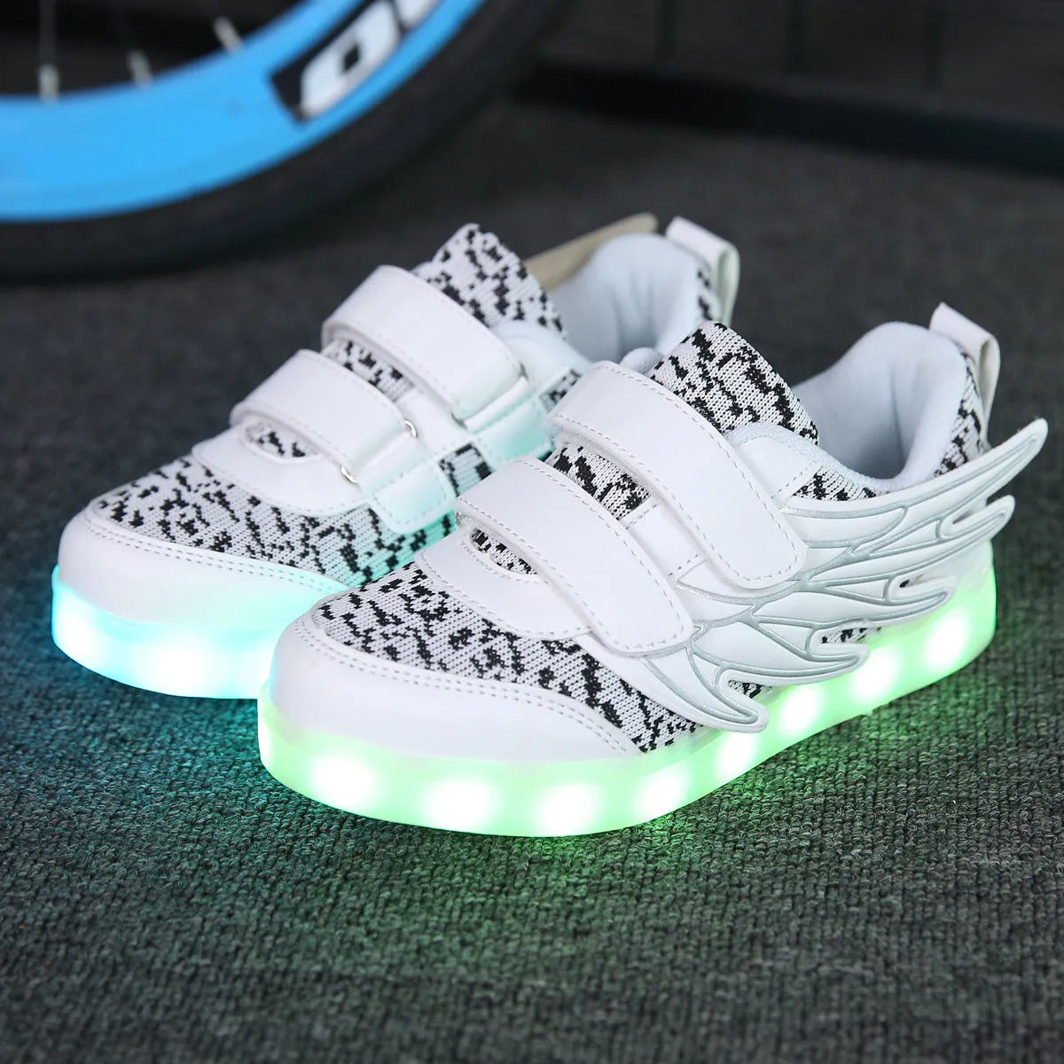 Plum red and white children's LED light-up sneakers showing USB charging port and hidden colour-selector switch.