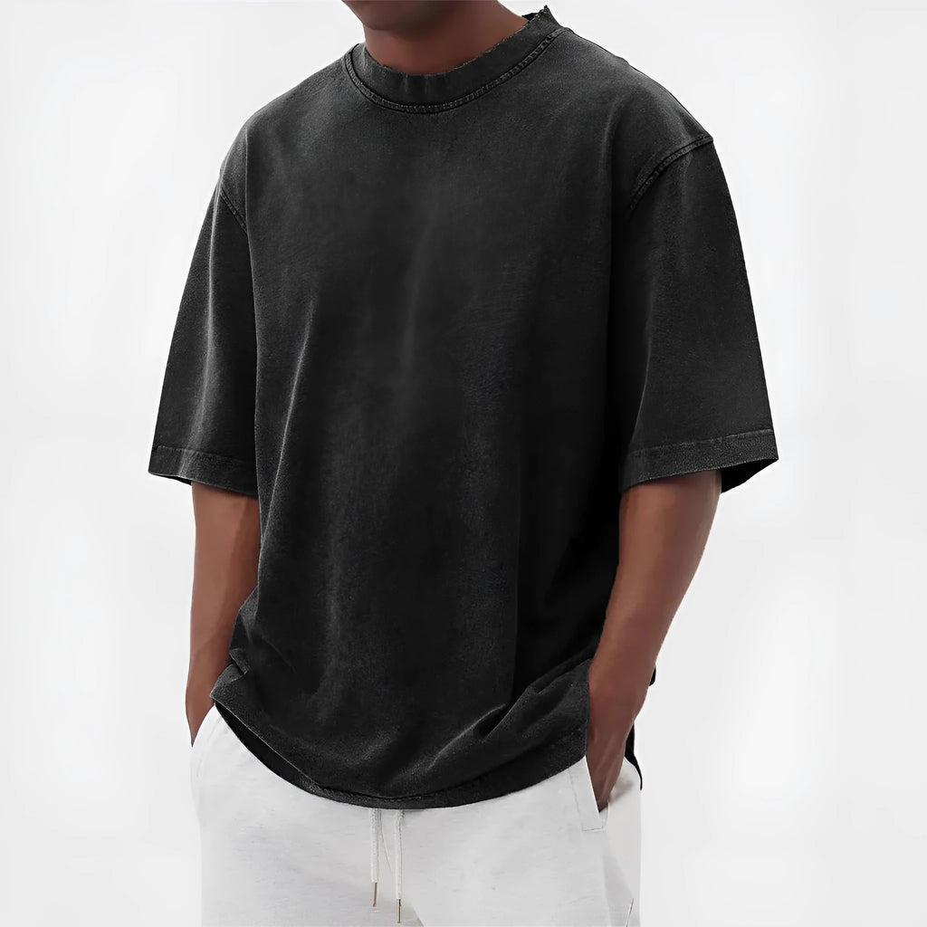 Man wearing a loose-fit, stone-washed grey t-shirt with a distressed solid colour finish and half sleeves.