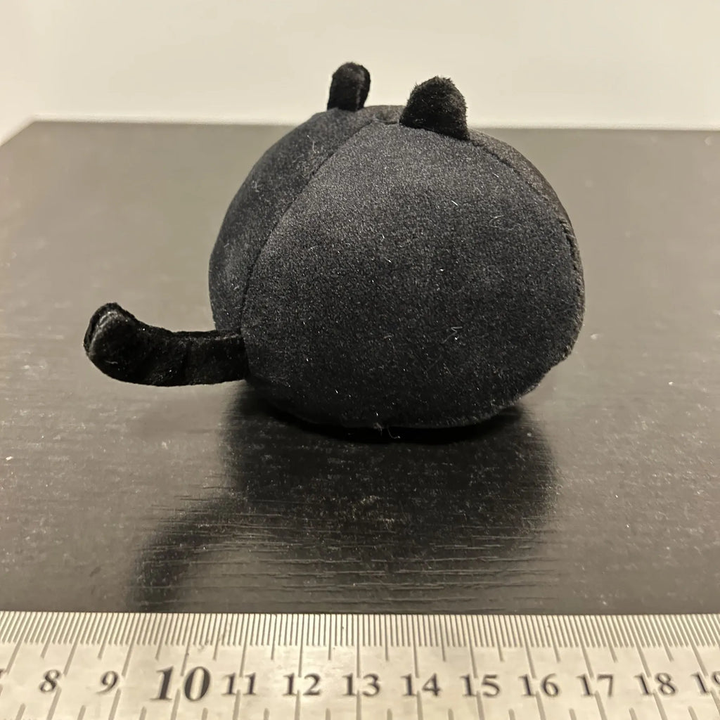 Black fluffy cat plush toy with printed face, sitting upright as a soft cushion.