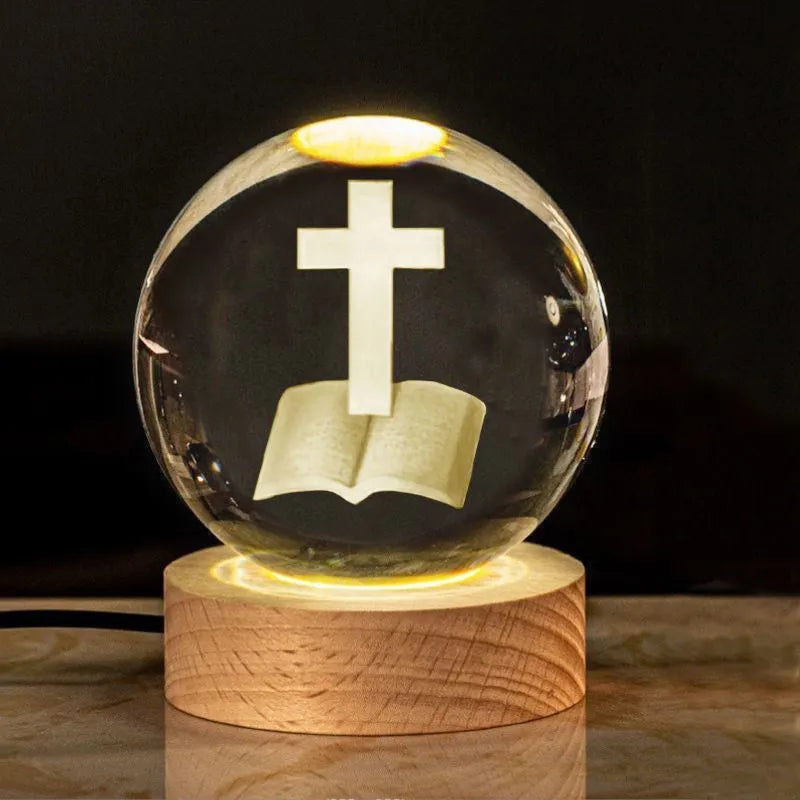 White crystal ball ornament on wood base with warm light and religious symbols