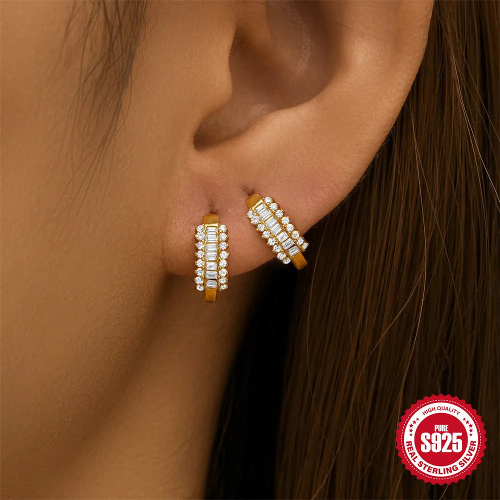 A pair of small, round, geometric stud earrings made of sterling silver with an electroplated finish.