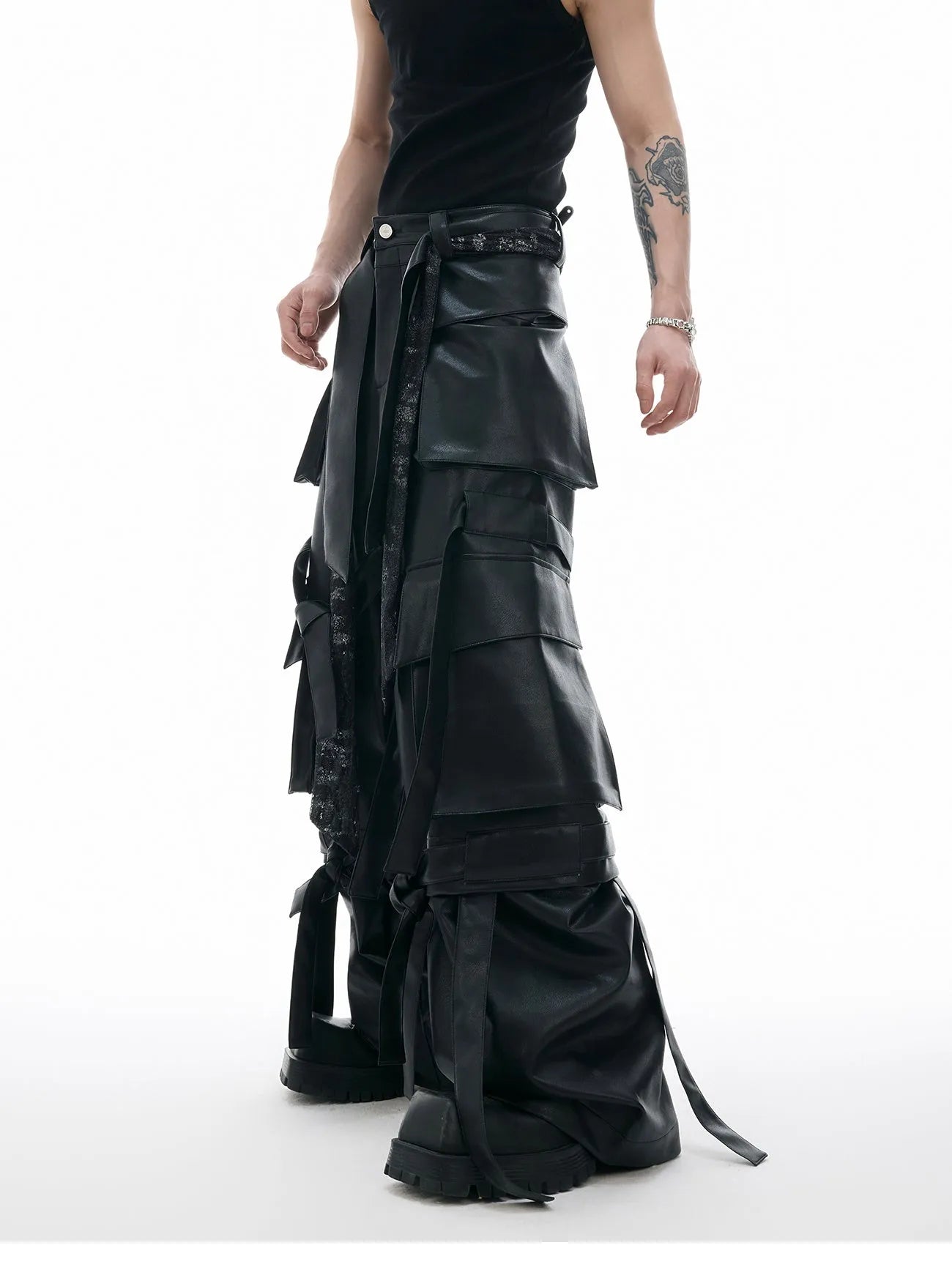 Black loose-fit men's trousers with multiple pockets, quilted panels, and decorative leather ribbon trim.
