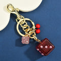 Vintage cherry two-tone square metal dice bag keychain pendant on a keyring.