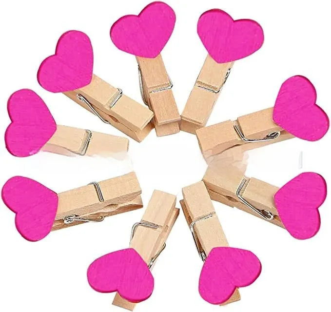 Five handmade solid wood heart-shaped clips in red, white, and pink on a wooden surface.