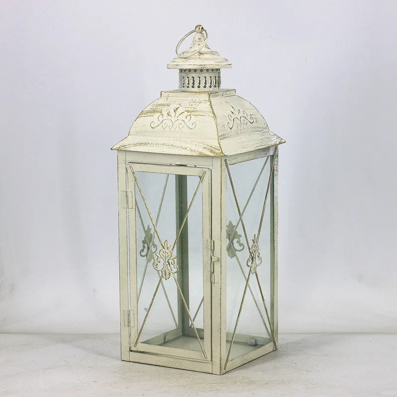 Black wrought iron floor lantern with glass panels on a stone patio.