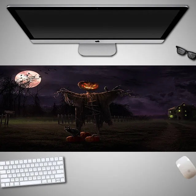 Oversized black Halloween-themed mouse pad with spooky artwork on a desk next to a gaming mouse.