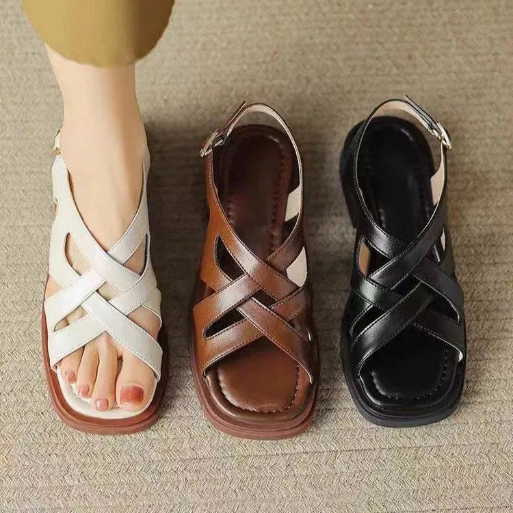 Glossy black patent leather women's sandals with a cross-band design, square toe, and low rubber sole.