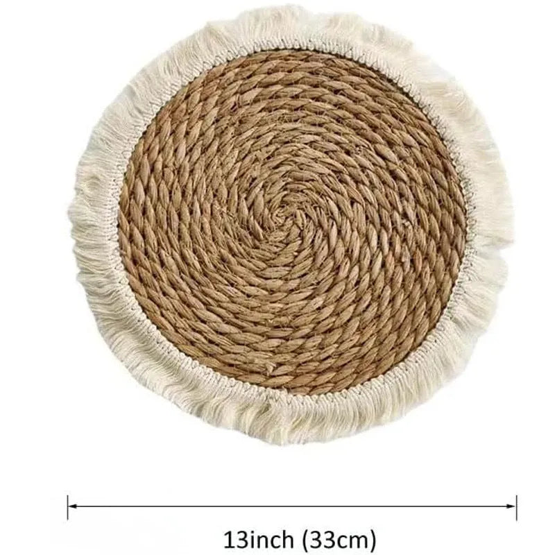 Round natural papyrus placemat with tassel trim on a wooden table.