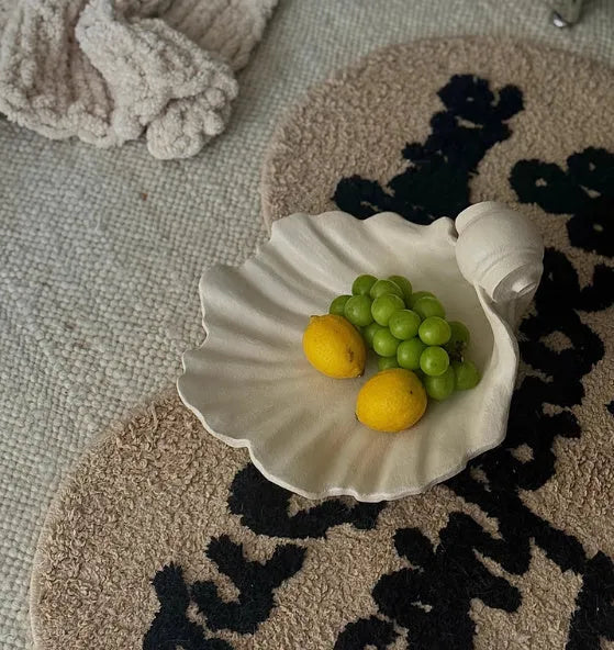 White resin shell-shaped fruit plate ornament on table setting