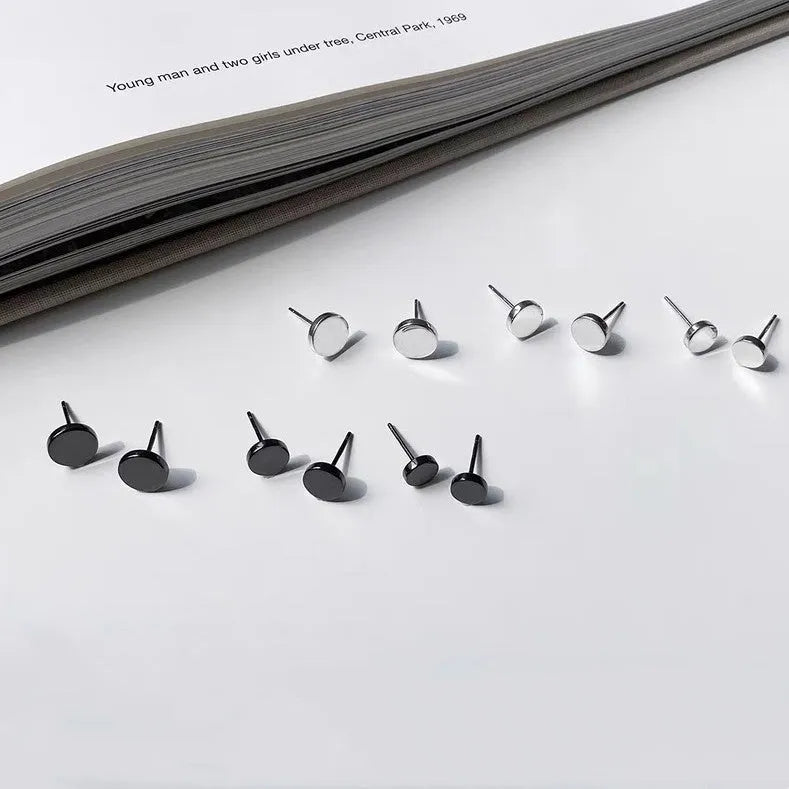 A pair of simple geometric round S999 Sterling Silver flat bone stud earrings in silver and black, showing size variation.