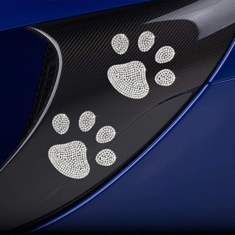 Close-up of a diamond-sparkle glass car sticker in a butterfly or bear paw design on a car surface.