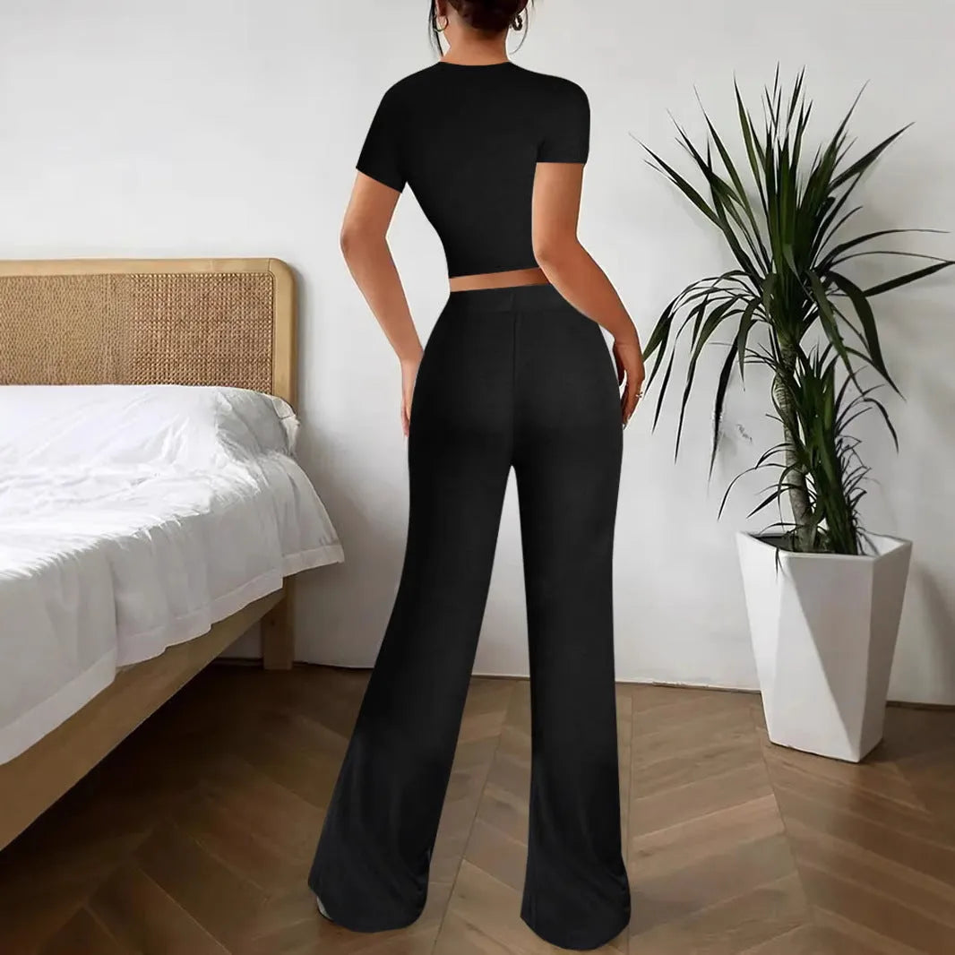 Black women's high waist trousers and short sleeve t-shirt co-ord set laid flat.