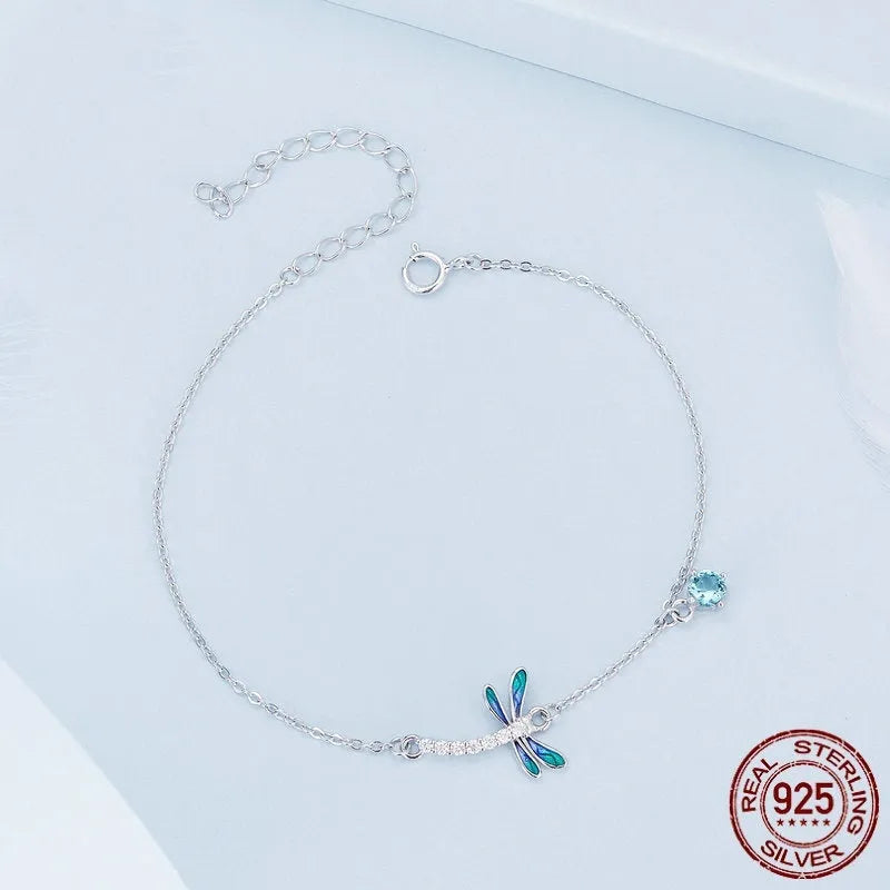 Sterling silver white gold plated dragonfly bracelet with dripping cubic zirconia stones on a light background