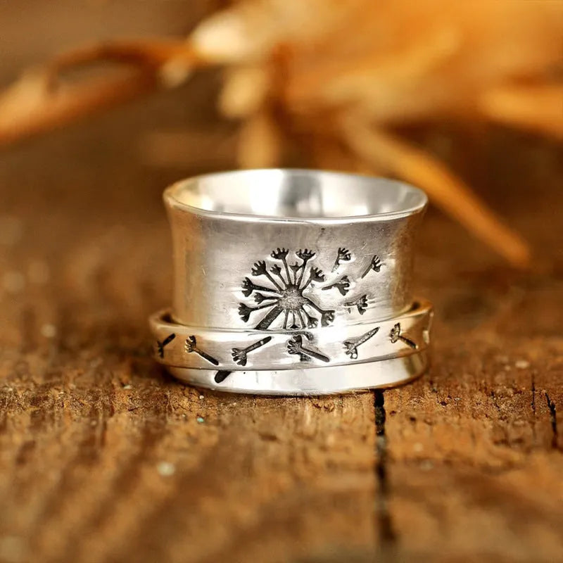 Silver coloured alloy flower ring with rotatable floral detail on a finger.